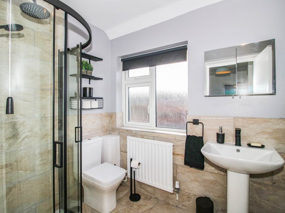 A bathroom with a shower, toilet, sink and window at 3 Jubilee Cottages in Pontesbury
