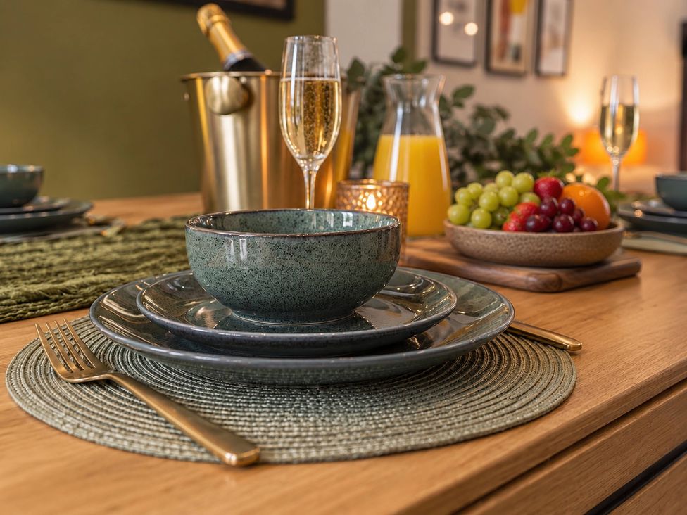 A dining table set with plates, bowls, glasses, fruit, and a champagne bucket at 20A Westend Parade, Gloucester