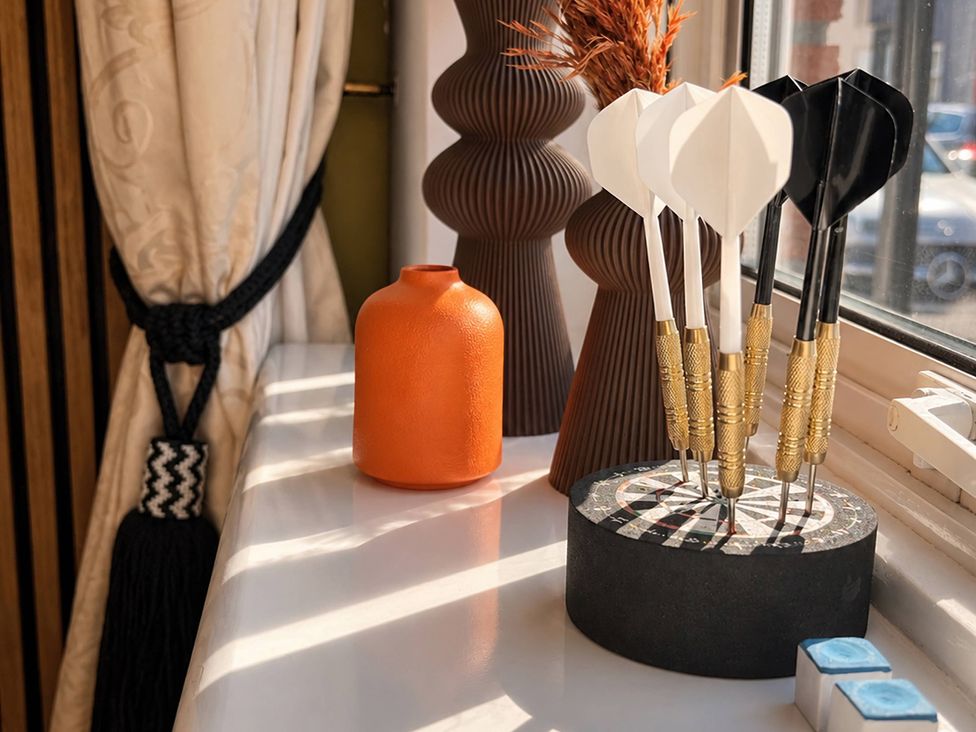 A window with darts on a dartboard and decorative vases at 20A Westend Parade in Gloucester