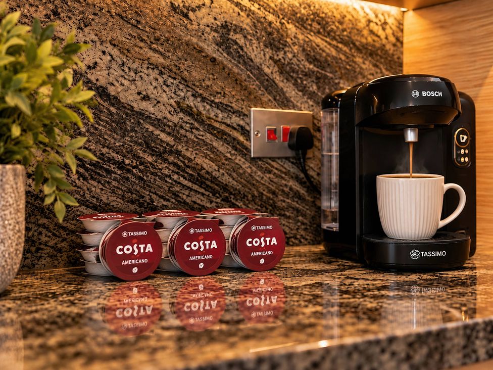 A coffee machine with cups and pods in a kitchen at 20A Westend Parade in Gloucester