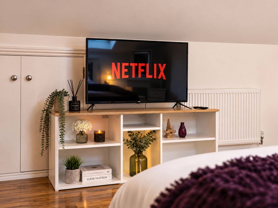 A living room with a television and shelves at 20A Westend Parade in Gloucester