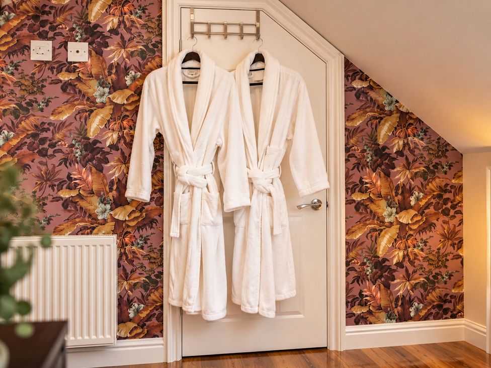A bathroom with robes hanging on a door at 20A Westend Parade in Gloucester