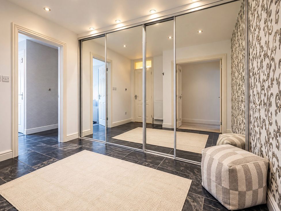 A hallway with a mirror and a striped pouffe at 20A Westend Parade in Gloucester
