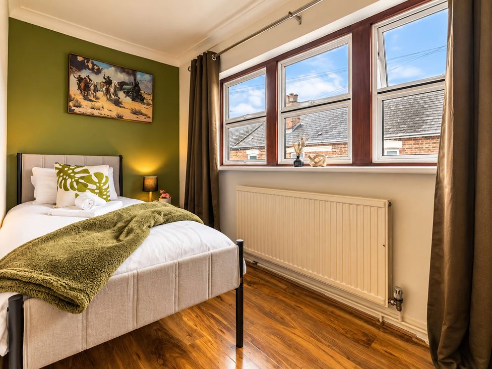 A bedroom with a bed, lamp, and window at 20A Westend Parade in Gloucester