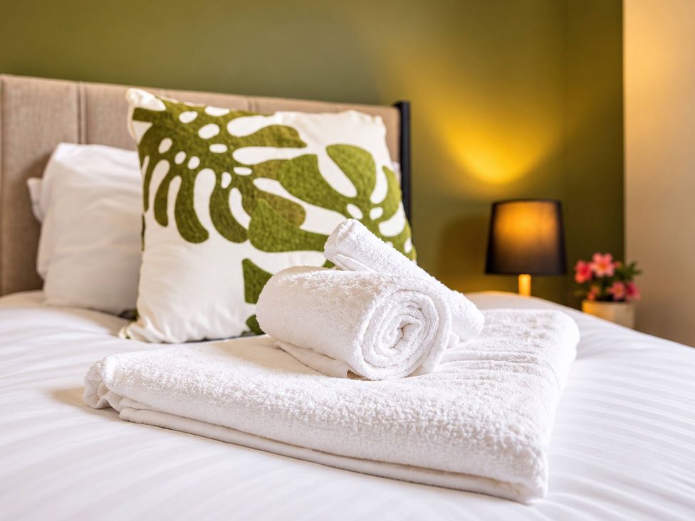 A bed with towels and a cushion at 20A Westend Parade in Gloucester