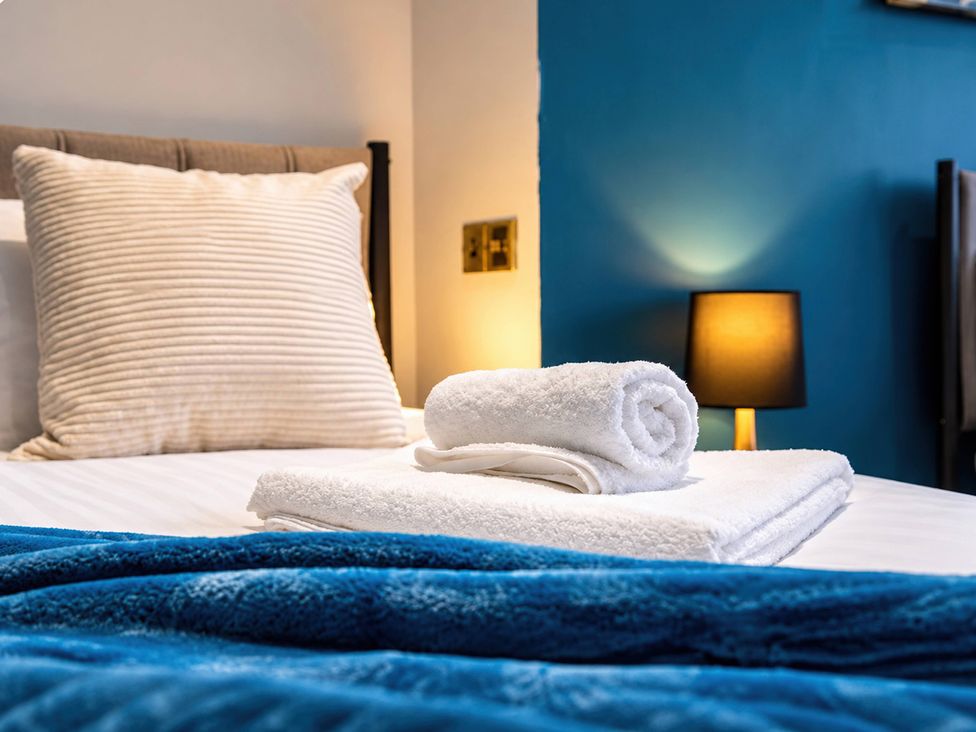 A bedroom with a bed, pillows, and towels at 20A Westend Parade in Gloucester