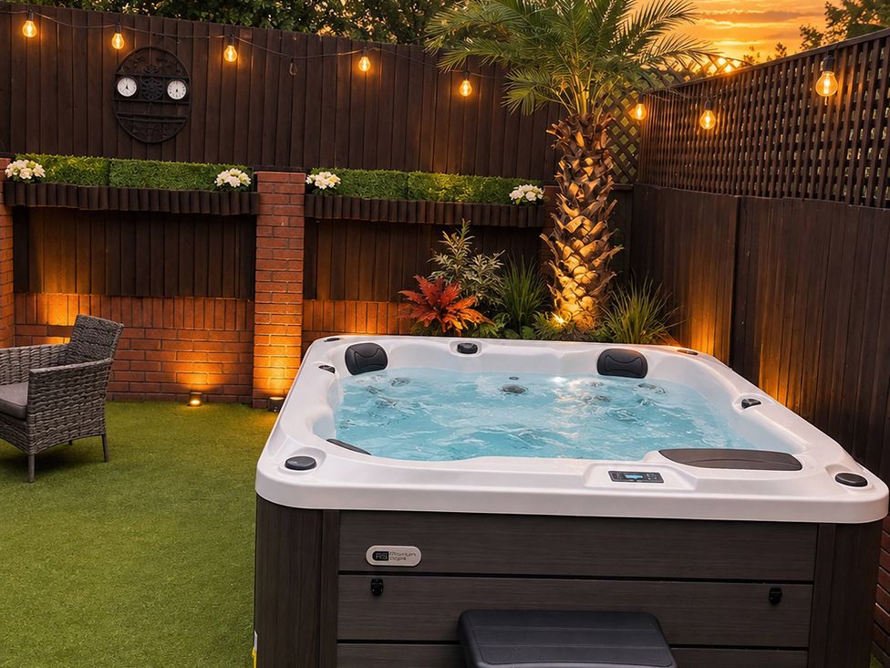 A garden with a hot tub and chair at 20A Westend Parade in Gloucester