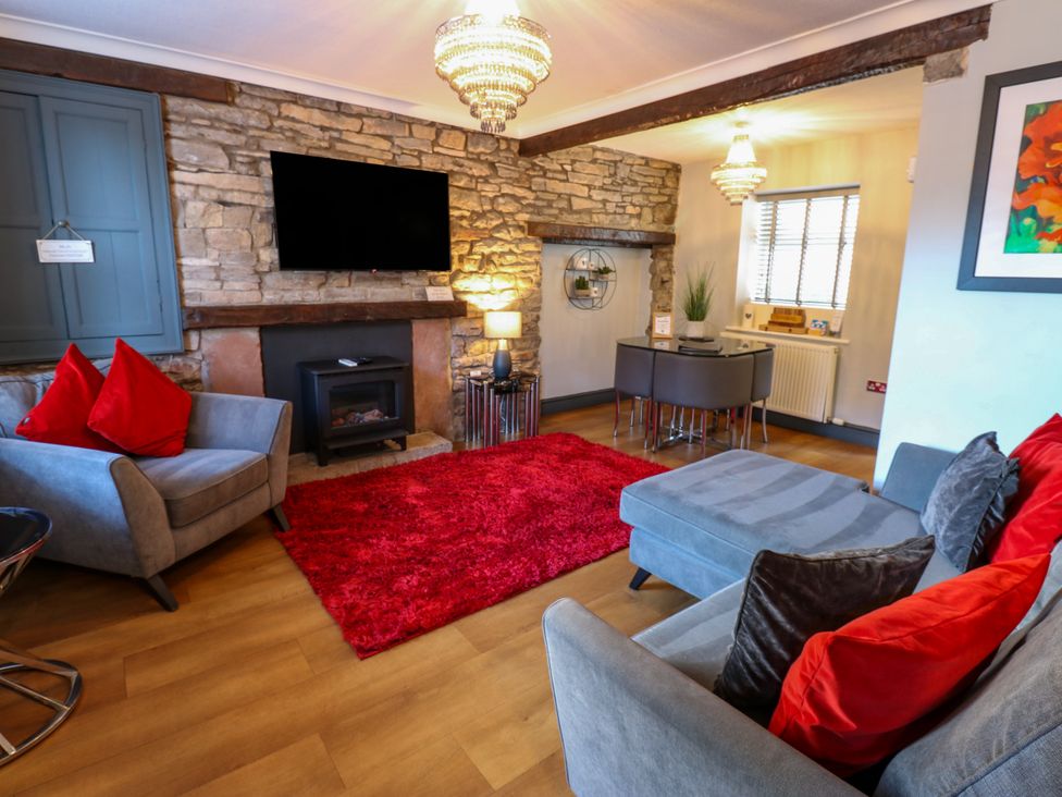 A living room with a sofa, armchair, and television at Crown Cottage in Appleby-In-Westmorland