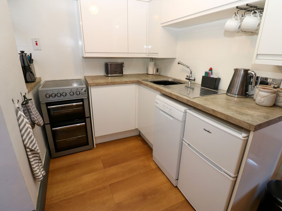 A kitchen with cabinets, stove, sink, refrigerator, and appliances at Crown Cottage in Appleby-In-Westmorland