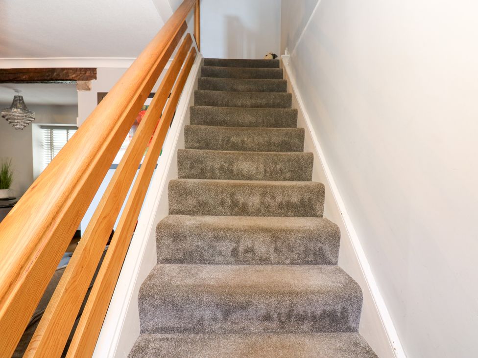 A staircase with a carpet and wooden banister at Crown Cottage Appleby-In-Westmorland