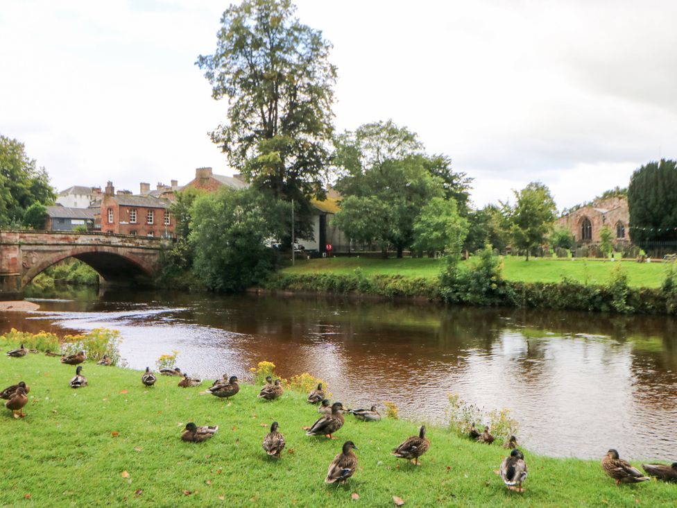 A river with ducks and a bridge near buildings at Crown Cottage in Appleby-In-Westmorland