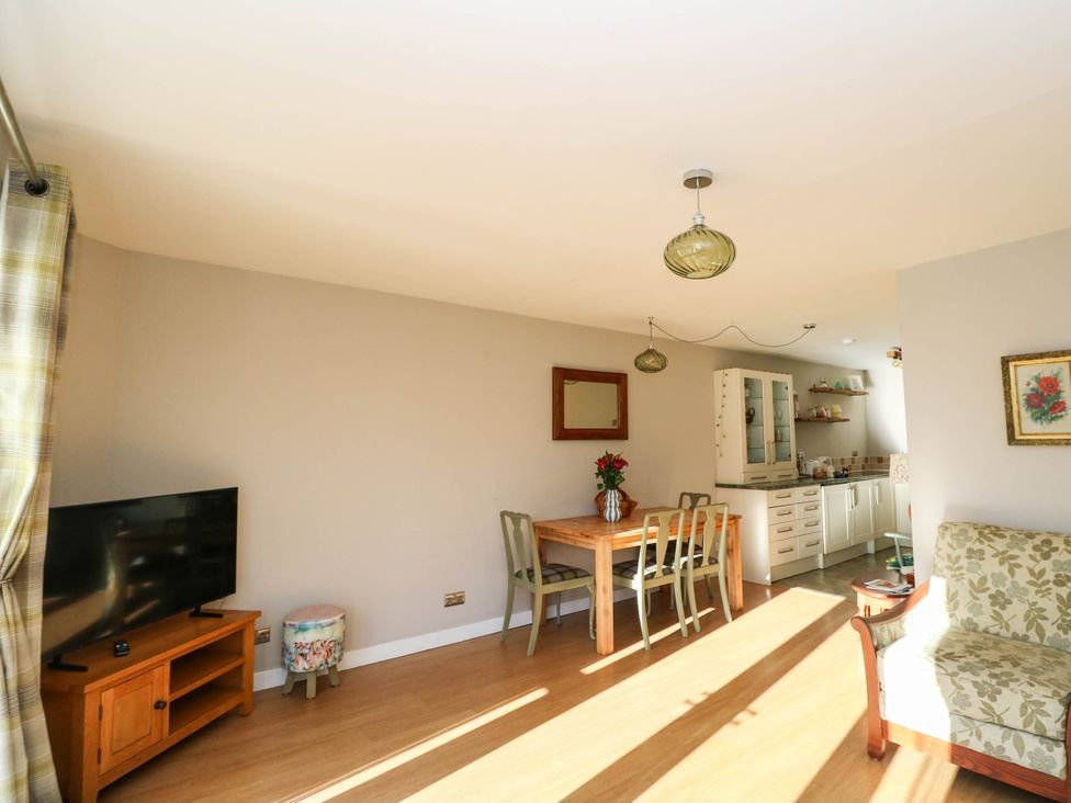 A dining room with a table and chairs beside a television at Moness Garden Studio Aberfeldy
