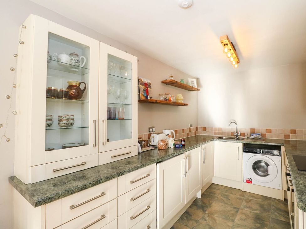 A kitchen with cupboards, shelves, kettle and washing machine at Moness Garden Studio Aberfeldy