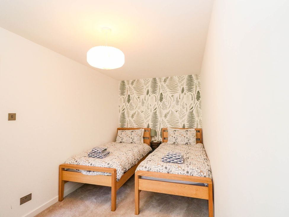 A bedroom with two beds and a patterned wallpaper at Moness Garden Studio in Aberfeldy