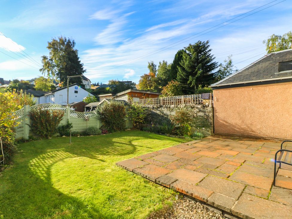 A garden with grass and a paved patio at Moness Garden Studio in Aberfeldy