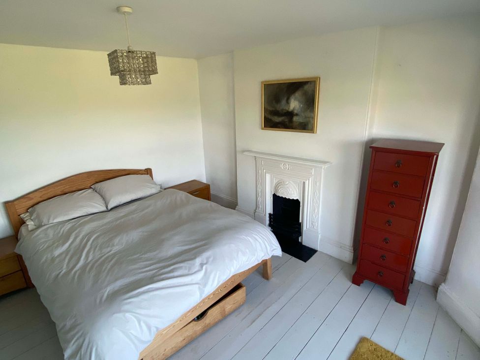 A bedroom with a bed and a red chest of drawers at Strand House in Treknow near Tintagel