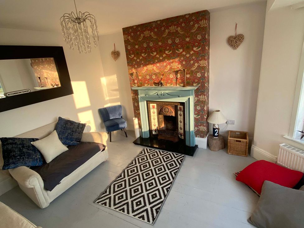 A living room with a fireplace and decorative pillows at Strand House Treknow near Tintagel
