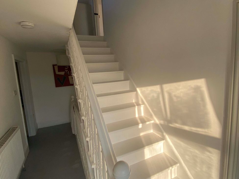 A staircase with white walls and a handrail at Strand House Treknow near Tintagel