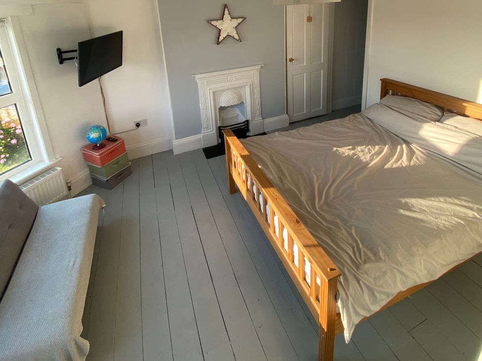 A bedroom with a bed, sofa, and television at Strand House in Treknow near Tintagel