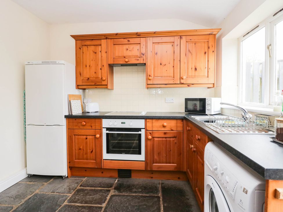 A kitchen with appliances and wooden cabinets at Acorn Cleator