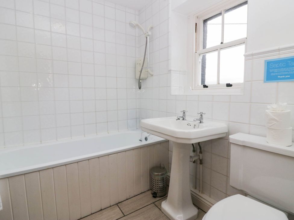 A bathroom with a bathtub, sink, and toilet at Acorn in Cleator