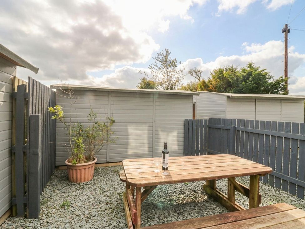 An outdoor area with a wooden table and a bottle on it at Acorn in Cleator