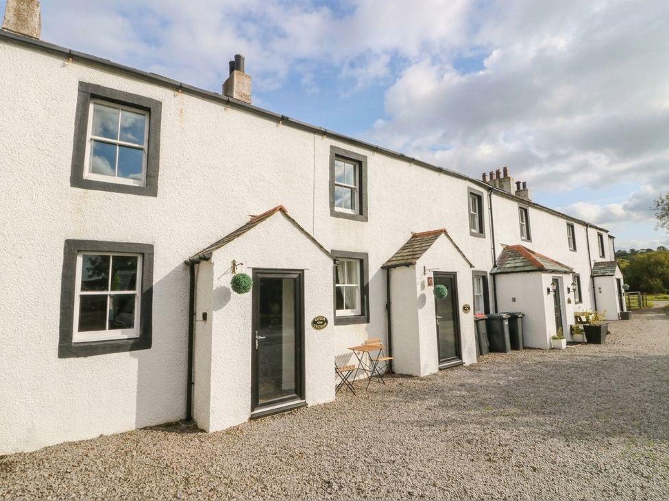 A row of houses with entrance doors and seating area at Acorn in Cleator