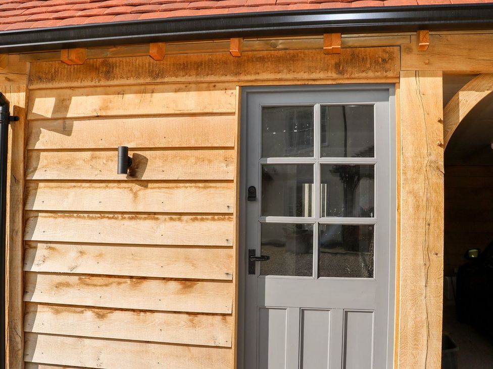 An entrance door with wooden wall and light fixture at The Granary 2 Bed in Bordon