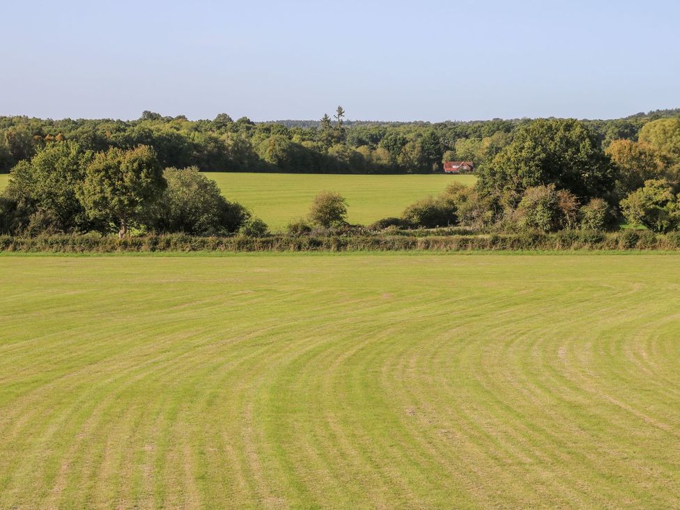A view of a field with trees and a house in the distance at The Granary 2 Bed Bordon