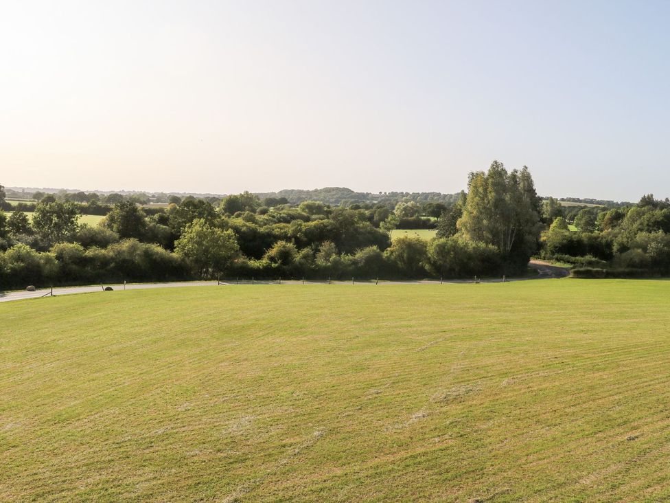 A view of a grassy field with trees and hills at The Granary 2 Bed in Bordon