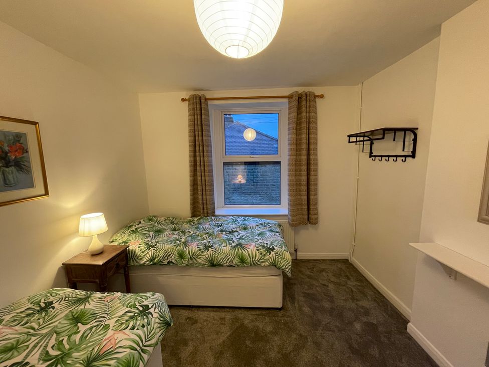 A bedroom with two beds and a window at 9 Market View in Buxton