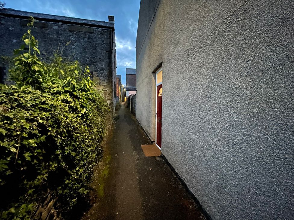 A pathway between buildings with a door on the right at 9 Market View Buxton