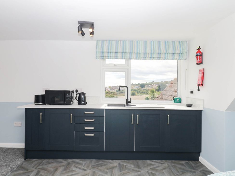 A kitchen with cabinets and appliances at Merlins Hideaway in Dawlish