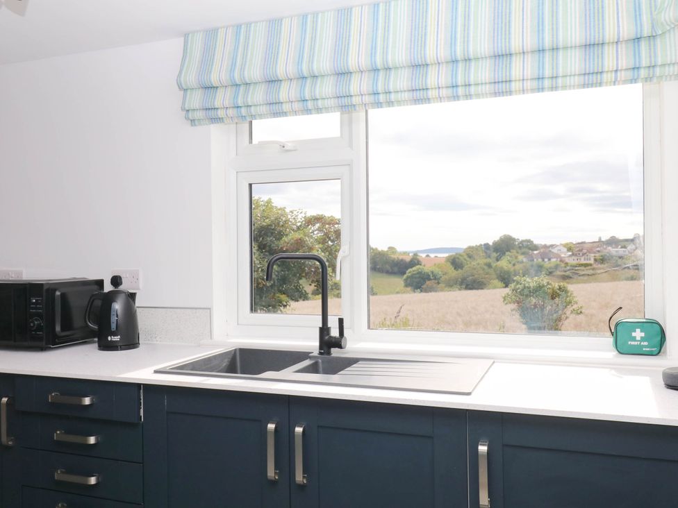 A kitchen with a sink, microwave, and kettle at Merlins Hideaway in Dawlish