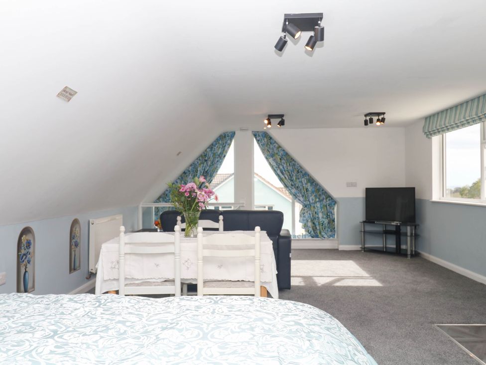 A loft with a bed and a seating area at Merlins Hideaway in Dawlish