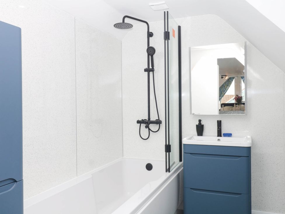 A bathroom with a bathtub and shower at Merlins Hideaway in Dawlish