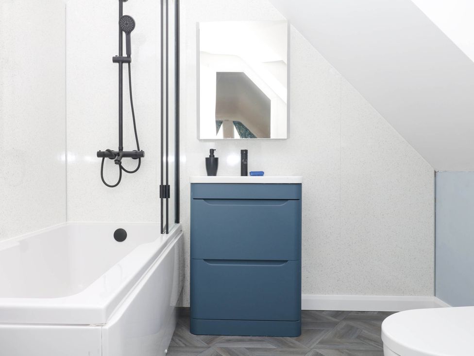A bathroom with a bathtub and sink at Merlins Hideaway in Dawlish