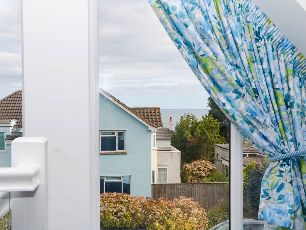 A view of houses and sea from a window at Merlins Hideaway in Dawlish