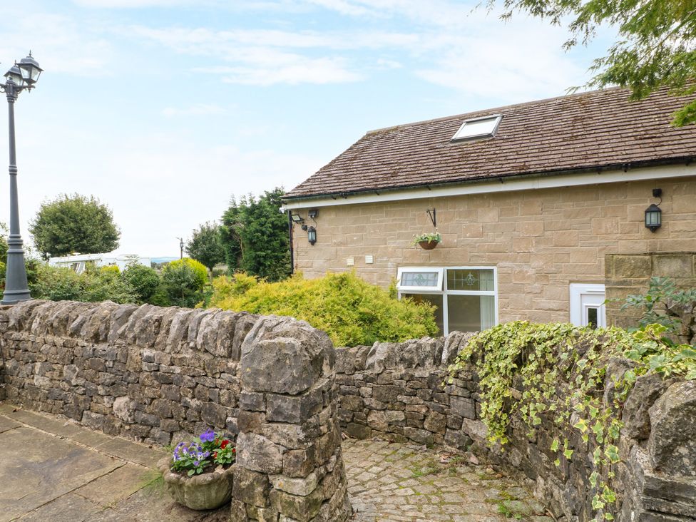 An outdoor area with a stone wall, door, and lamp post at Greystones - Apartment B near Buxton
