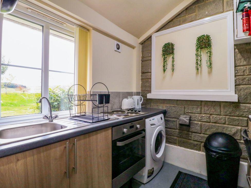 A kitchen with a sink, kettle, washing machine and a window at Greystones - Apartment C near Buxton