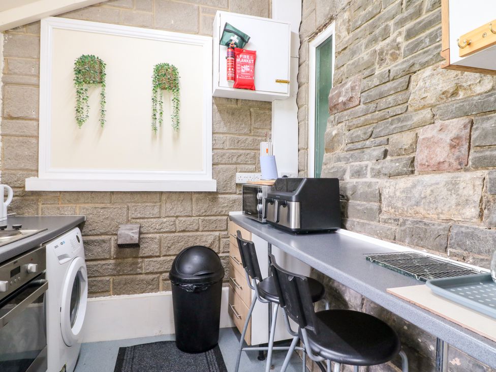 A kitchen with appliances and bar stools at Greystones - Apartment C near Buxton