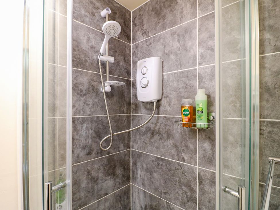 A shower with glass doors and tiled walls at Greystones - Apartment C near Buxton