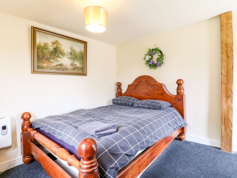 A bedroom with a wooden bed and wall art at Greystones - Apartment C near Buxton