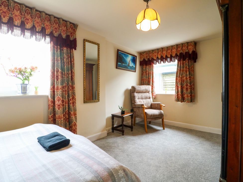 A bedroom with a bed, armchair, and window at Greystones - apartment D near Buxton