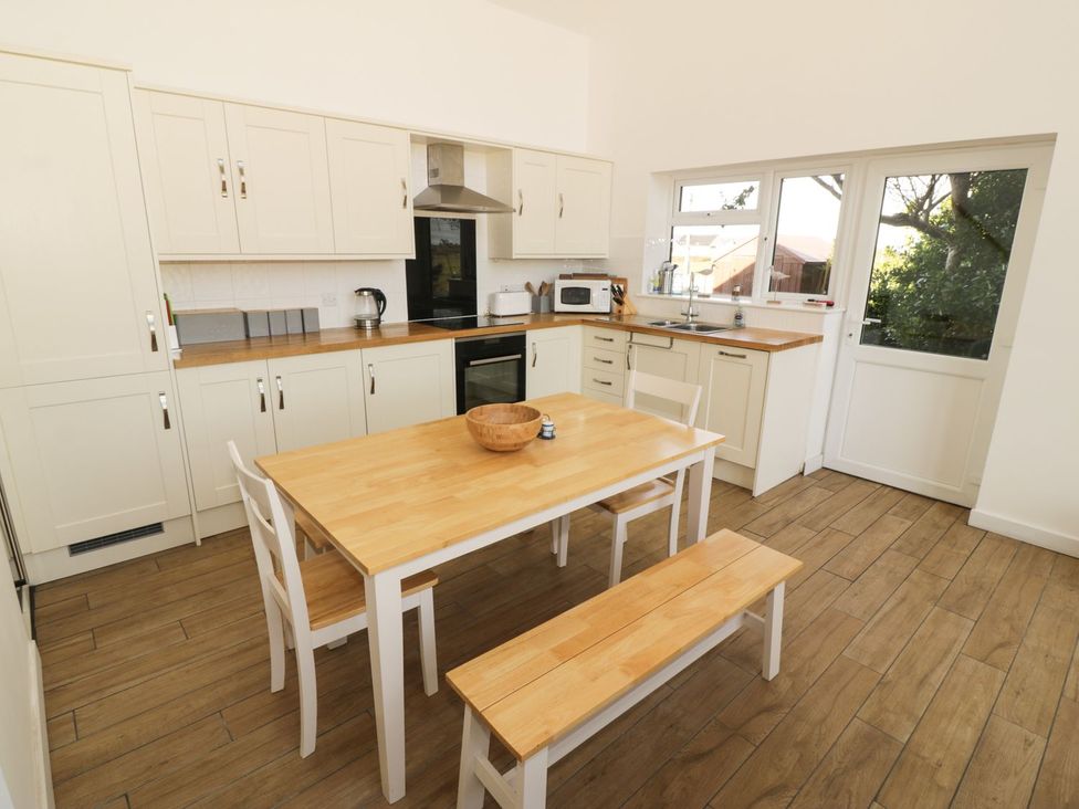 A kitchen with wooden table and chairs at Cae Mawr in Caernarfon