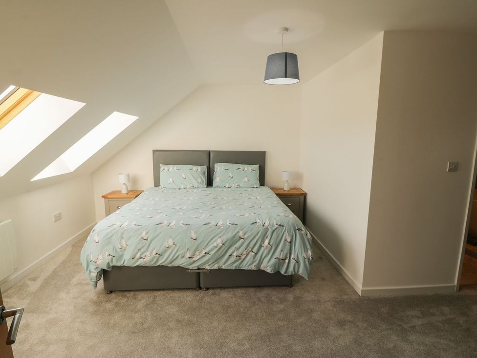 A bedroom with a bed, lamp and nightstand at Cae Mawr in Caernarfon