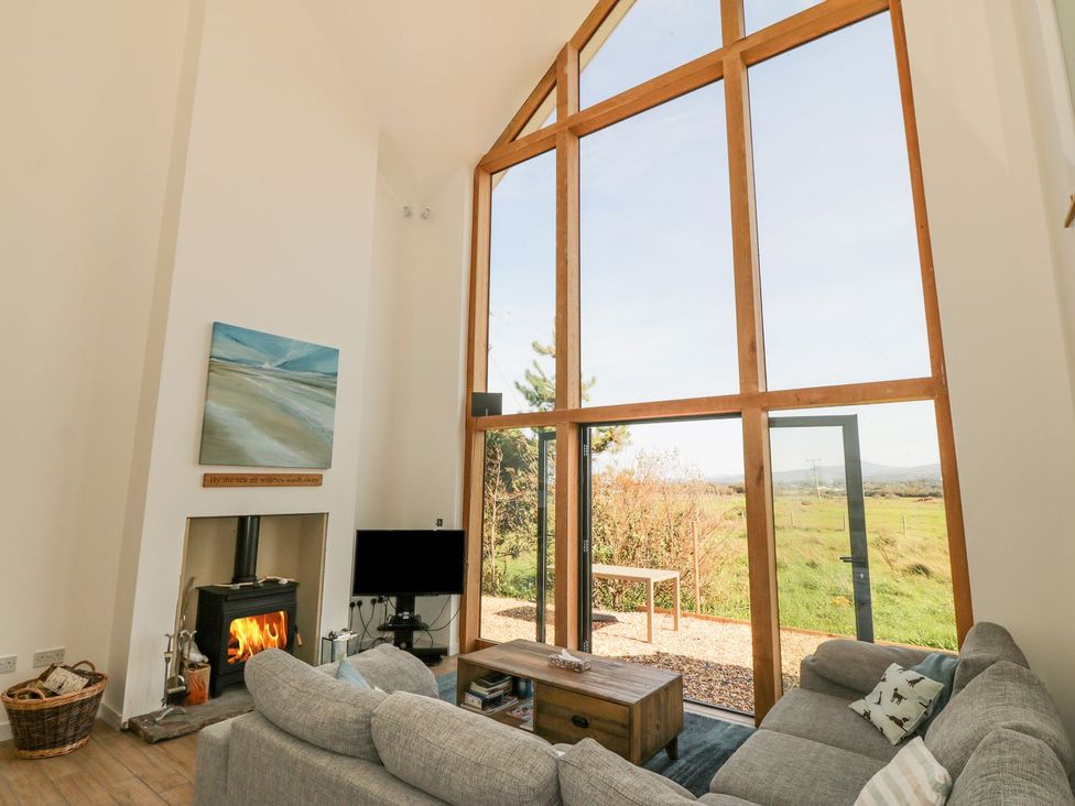 A living room with a large window and a fireplace at Cae Mawr in Caernarfon