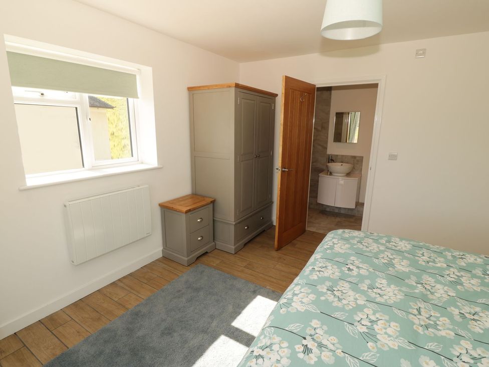 A bedroom with a bed, wardrobe and window at Cae Mawr in Caernarfon