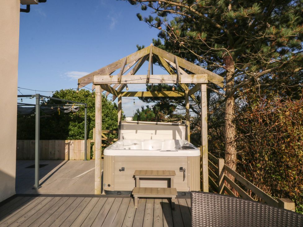 An outdoor area with a hot tub and wooden gazebo at Cae Mawr Dinas Dinlle