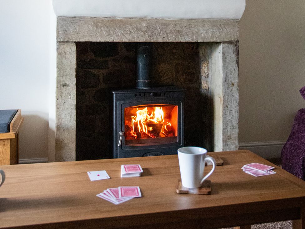 A living room with a fireplace and playing cards on a table at Gap Farm in Brampton